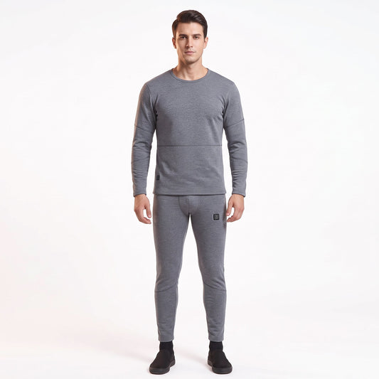 Full-body front view of a male model wearing a matching two-piece gray smart heated thermal underwear set. The crew neck top has two black control icons at the hem, paired with full-length leggings against a solid white background.