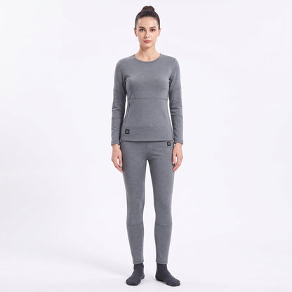 Full-body front view of a female model wearing a matching two-piece gray smart heated thermal underwear set. The crew neck top has two black control icons at the hem, paired with full-length leggings against a solid white background.